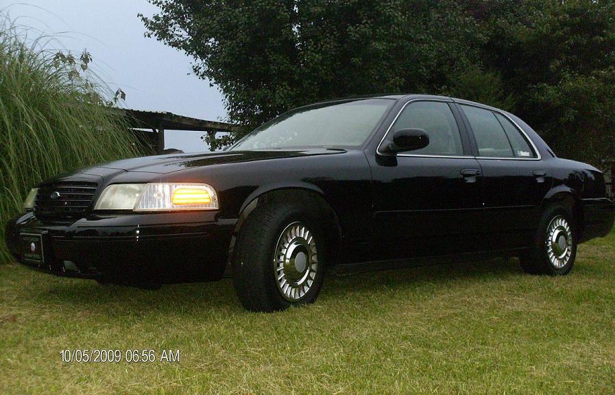 Black Ford Crown Victoria sedan parked on grass