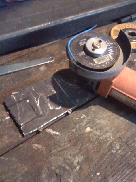 1989 Ford Bronco - A metal plate with etched markings sits on a workbench next to an angle grinder.