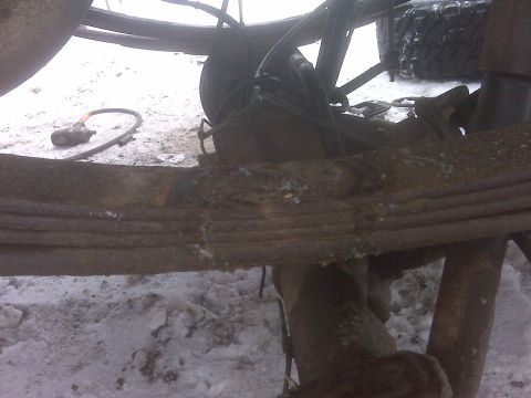 1994 Ford F-150 - The rear suspension and axle components of a truck are shown in this close-up view, with snow covering the ground.