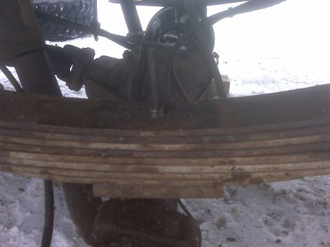 1994 Ford F-150 - Close-up view of a vehicle's rusty leaf spring suspension system in a snowy environment.