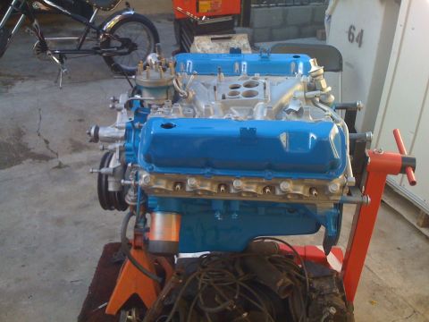 1979 Ford Bronco - A blue V8 engine is mounted on an orange engine stand, with a bicycle visible behind it.