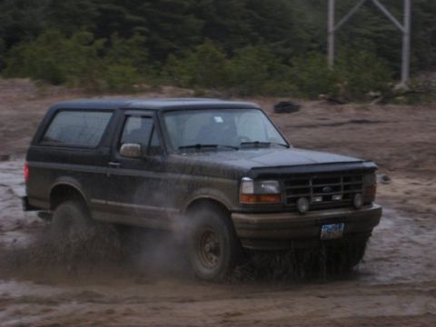 1994 Ford Bronco - 1994 Ford Bronco navigating a muddy off-road trail.