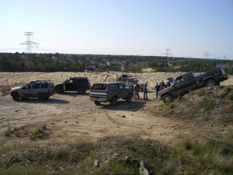 1994 Ford Bronco - A group of people gather around a brown 1994 Ford Bronco in an off-road setting.
