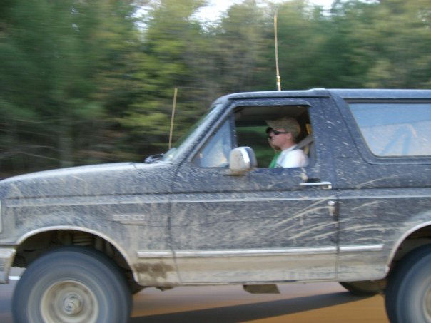 Side view of a muddy 1994 Ford Bronco with a driver wearing sunglasses