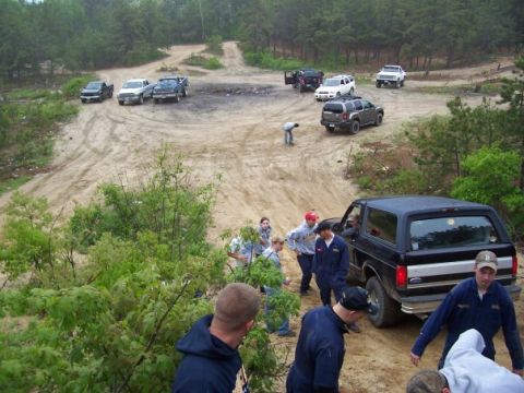 1994 Ford Bronco - Several vehicles are gathered on a dirt track, with a black Ford Bronco prominently in the foreground.
