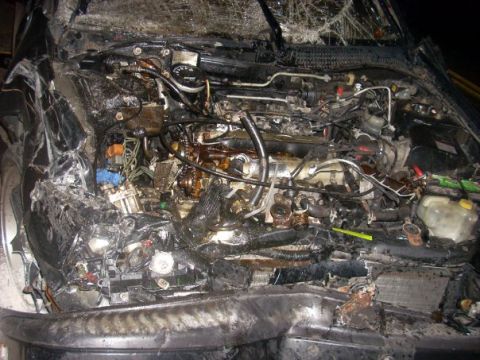 1996 Ford Bronco - The engine compartment of a vehicle shows severe damage from a fire and collision.