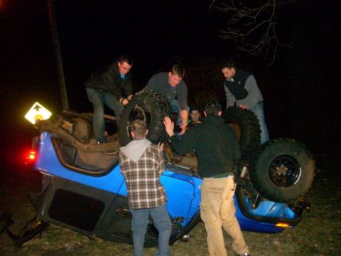 1996 Ford Bronco - Several people surround an overturned blue Jeep, possibly after an accident.