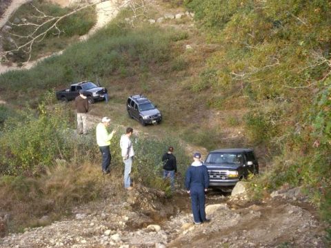 1994 Ford Bronco - A group of people observe as multiple vehicles traverse a challenging off-road trail.