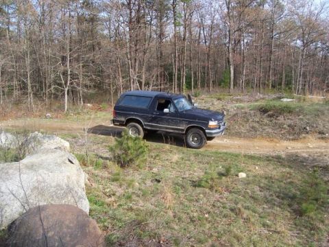 1994 Ford Bronco - This black 1994 Ford Bronco is seen off-road in a wooded area.