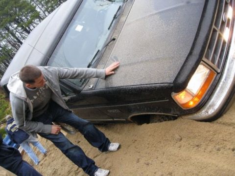 1994 Ford Bronco - A man attempts to free a black SUV that is stuck in a sandy ditch.