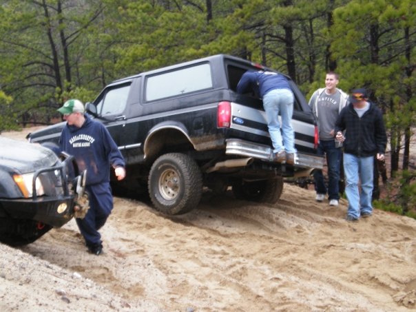 Black 1994 Ford Bronco on a sandy trail with people around it