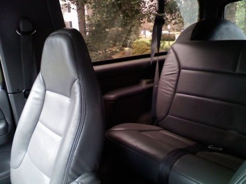 1994 Ford Bronco - The interior of a vehicle shows two rows of leather seats, with seatbelts visible.