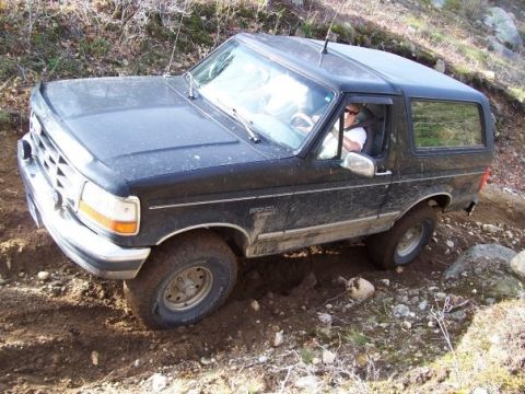 1994 Ford Bronco - This black 1994 Ford Bronco is shown off-roading on a dirt path with rocky inclines.