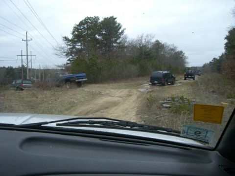 1994 Ford Bronco - Multiple SUVs and a pickup truck are on a dirt road in a wooded area.