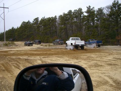 1994 Ford Bronco - Off-roading with multiple trucks and SUVs in a sandy, wooded area.
