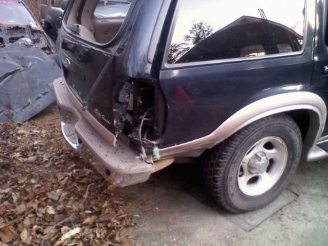 2000 Ford Explorer - The rear quarter panel and bumper of a dark SUV, likely a 2000 Ford Explorer, show significant damage to the taillight assembly.