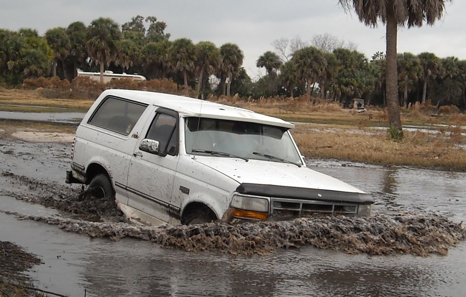 White 1992 Ford Bronco stuck in mud, front end submerged