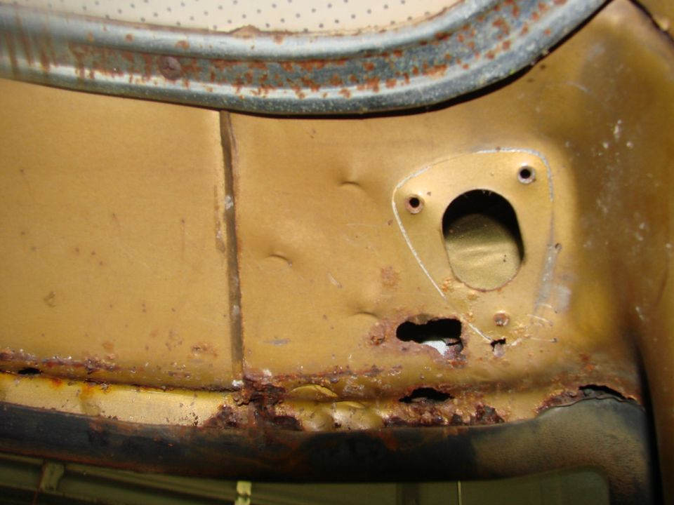 Yellow vehicle inner panel with rust and an access hole
