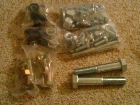 1995 Ford Bronco - Bags of assorted hardware and fasteners, including nuts and bolts, laid out on a carpeted surface.
