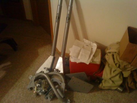 1995 Ford Bronco - A collection of metal parts, including two poles and a complex assembly, are laid out on the floor.