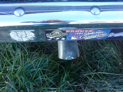 1995 Ford Bronco - A chrome exhaust pipe is visible below a bumper adorned with a sticker celebrating the 1995 World Series Champions.