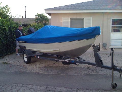 1968 Ford Mustang - A man stands next to a boat covered by a blue tarp, parked on a trailer.