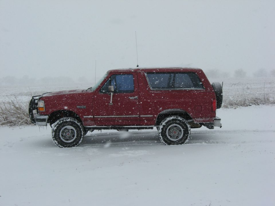red SUV parked in snow, spare tire on back