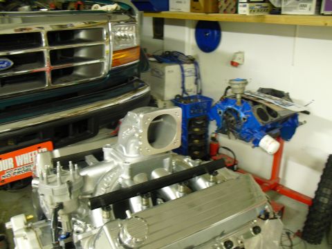 1996 Ford Bronco - A green Ford truck is parked next to a disassembled engine in a garage setting.
