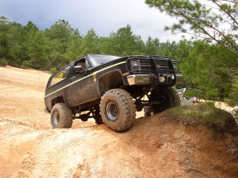 1991 Ford Bronco - This modified SUV is tackling a steep dirt incline, its off-road capabilities.