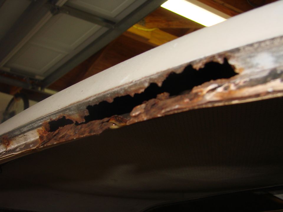 Rusted roof edge with large holes, showing interior fabric