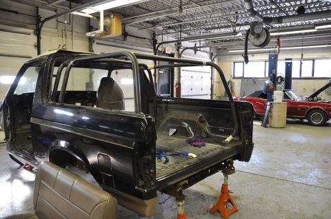 1996 Ford Bronco - This 1996 Ford Bronco is undergoing repairs in a garage, with another red convertible visible in the background.