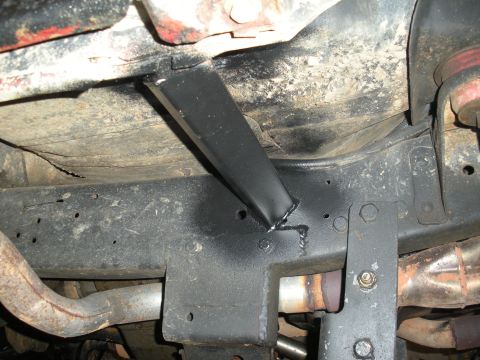 1979 Ford Bronco - Underbody detail of a black-painted square tube welded to the frame rail and crossmember, the fresh weld beads still visible at the joint,…