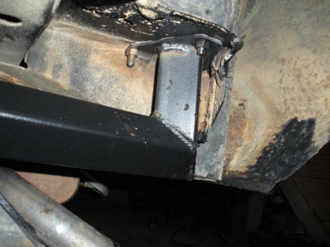 1979 Ford Bronco - Close-up of a fabricated steel roll cage mounting foot welded to a square tube and bolted through a cut opening in a rusty vehicle floor pa…