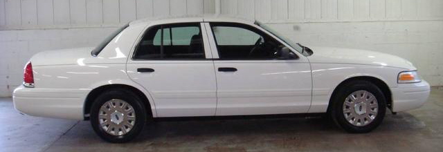 White Ford Crown Victoria sedan side profile with hubcaps on a white backdrop