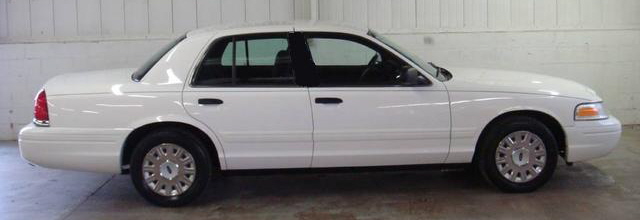 White sedan parked indoors, side view. Looks like a Ford Crown Victoria