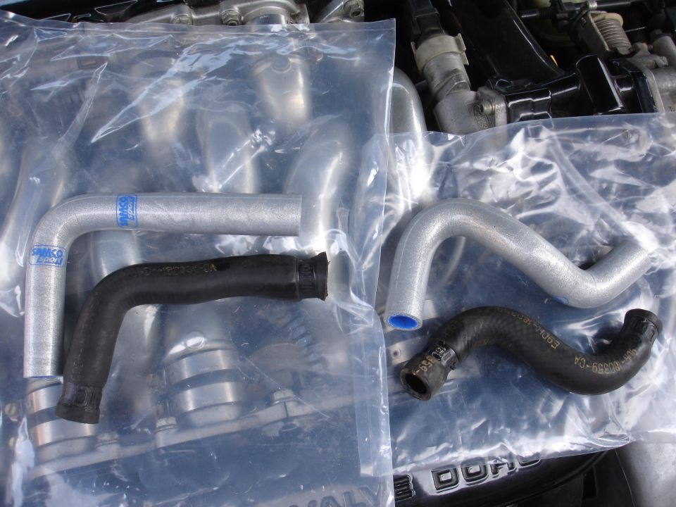 Four new radiator hoses, two silver and two black, laid out on an engine