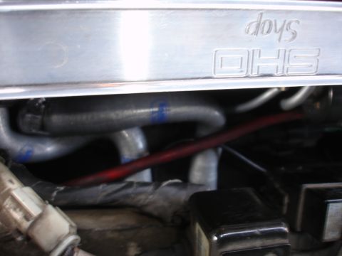 1993 Ford Taurus - Close-up of engine bay components including hoses and wiring, with embossed text on a metal cover.
