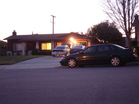 1993 Ford Taurus - Three cars are visible in front of a suburban house at dusk.