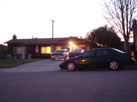 1993 Ford Taurus - A dark sedan is parked in the driveway of a suburban home at dusk, with other vehicles visible in the garage.