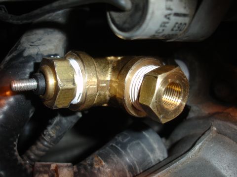 1993 Ford Taurus - A close-up view of a brass plumbing fitting with white sealant, connected to engine parts.