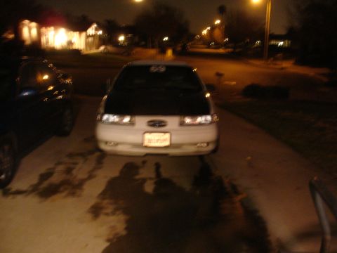 1993 Ford Taurus - A 1993 Ford Taurus is parked in a driveway at night, showing its front end and a license plate.