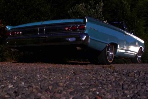 1969 Lincoln Continental - The rear of a teal convertible shows off its chrome bumper and triple taillights.