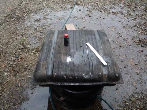 1969 Lincoln Continental - A fuel tank sits on a barrel outdoors, with a bottle and ruler on its surface.