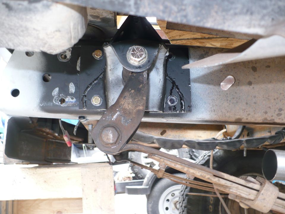 Underbody shot of welded black steering box mount plate on truck frame with rusty pitman arm