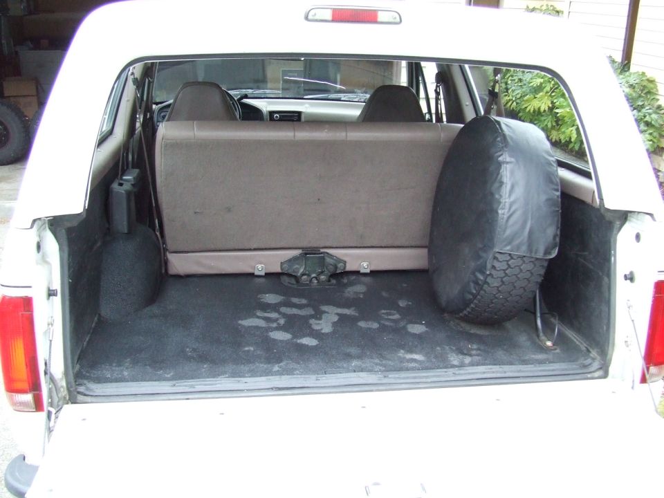 1996 Ford Bronco interior cargo area showing rear bench seat, spare tire, and carpeted floor