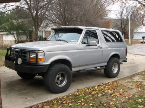 1992 Ford Bronco - A silver 1992 Ford Bronco is parked on a concrete driveway with fallen leaves scattered around.