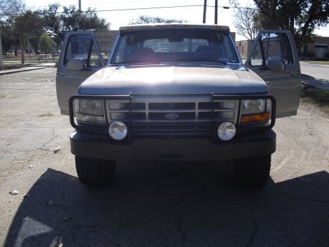 1992 Ford Bronco - The front of a 1992 Ford Bronco is shown with its doors open, parked on an asphalt surface.