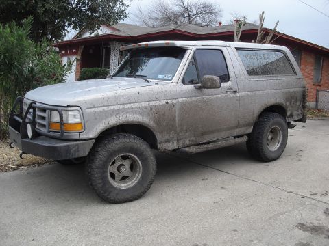 1992 Ford Bronco - This muddy 1992 Ford Bronco is parked in front of a house.