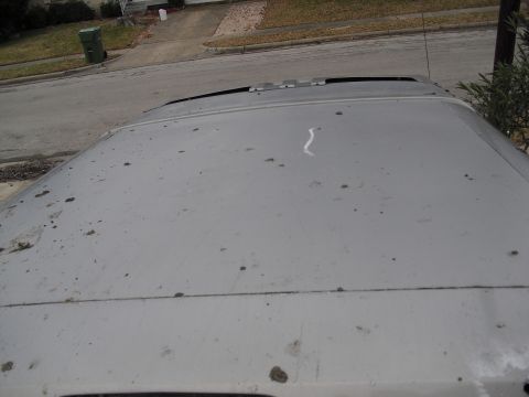 1992 Ford Bronco - The vehicle's roof is covered in dust and debris, obscuring any potential details about its make or model.