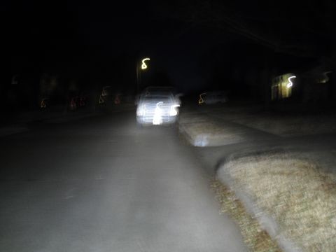 1992 Ford Bronco - A car is seen driving at night, its headlights illuminating the road ahead. The image is blurry due to motion.